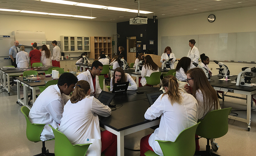 Loudoun County Public School students use microscopes to examine parasite samples and laptops to conduct virtual PCR labs in one of the wet labs in Discovery Hall.