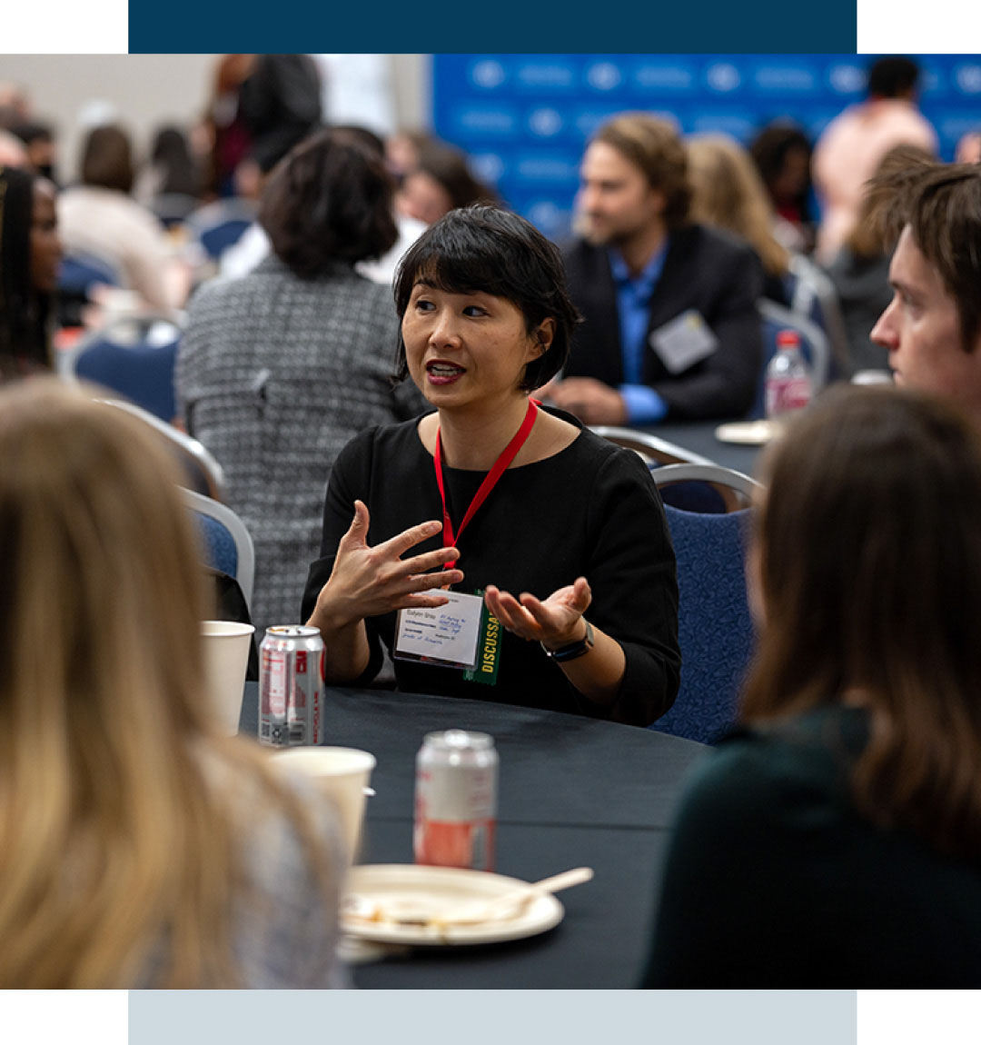 Woman talking at roundtable discussion with more groups in the background
