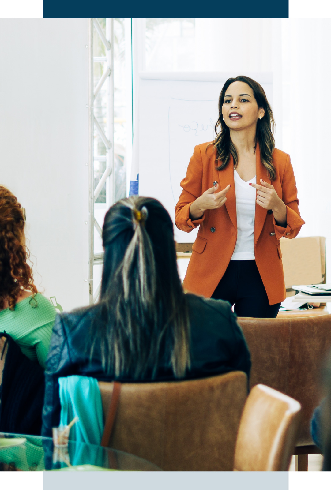 Woman in orange blazer talking to class