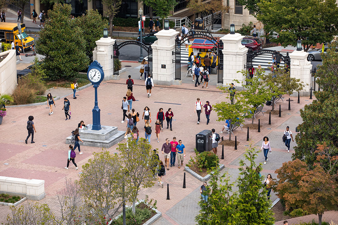 GW campus quad with bricks, tall clock, trees, students milling about