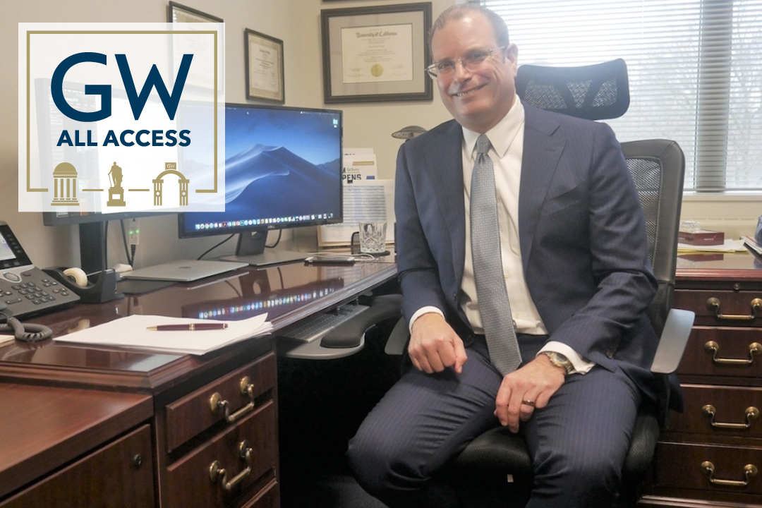Todd Belt at his desk, GW all access logo to his left