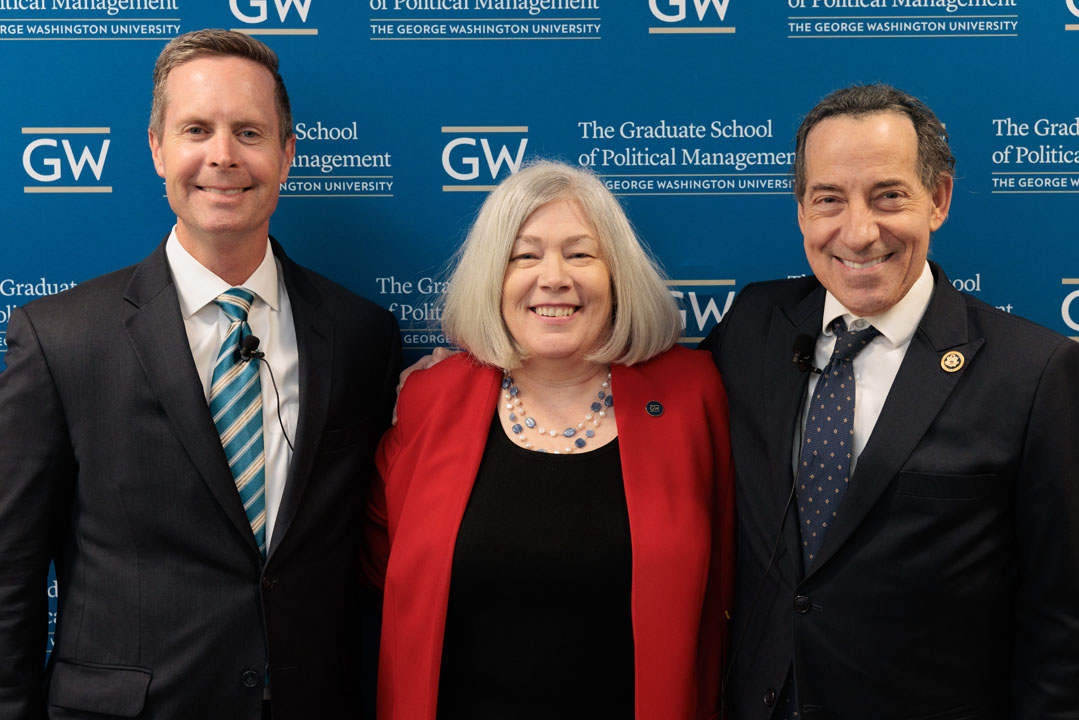 Rodney Davis, Ellen Granberg and Jamie Raskin posing and smiling in front of step-and-repeat