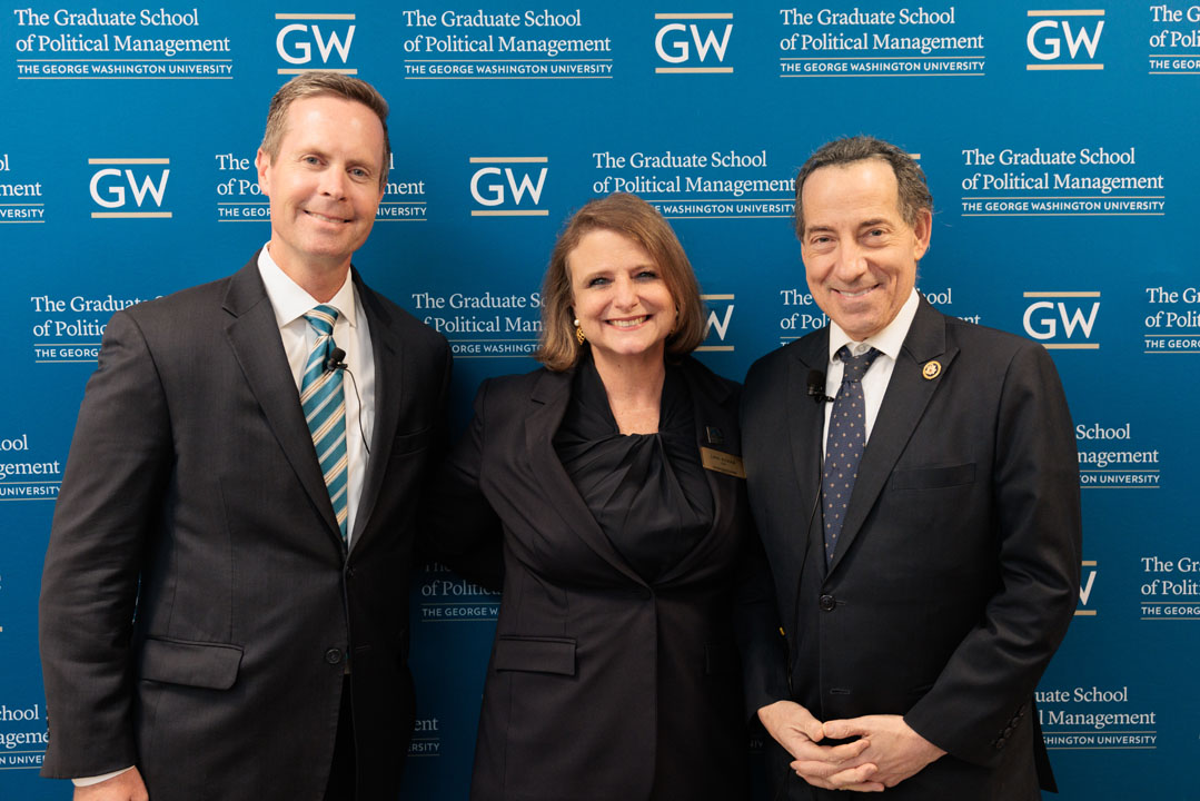 Rodney Davis, Liesl RIddle and Jamie Raskin smiling in front of step-and-repeat