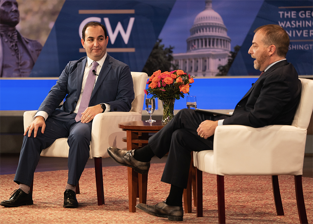 Weil and Todd speaking on a stage with GW logo background