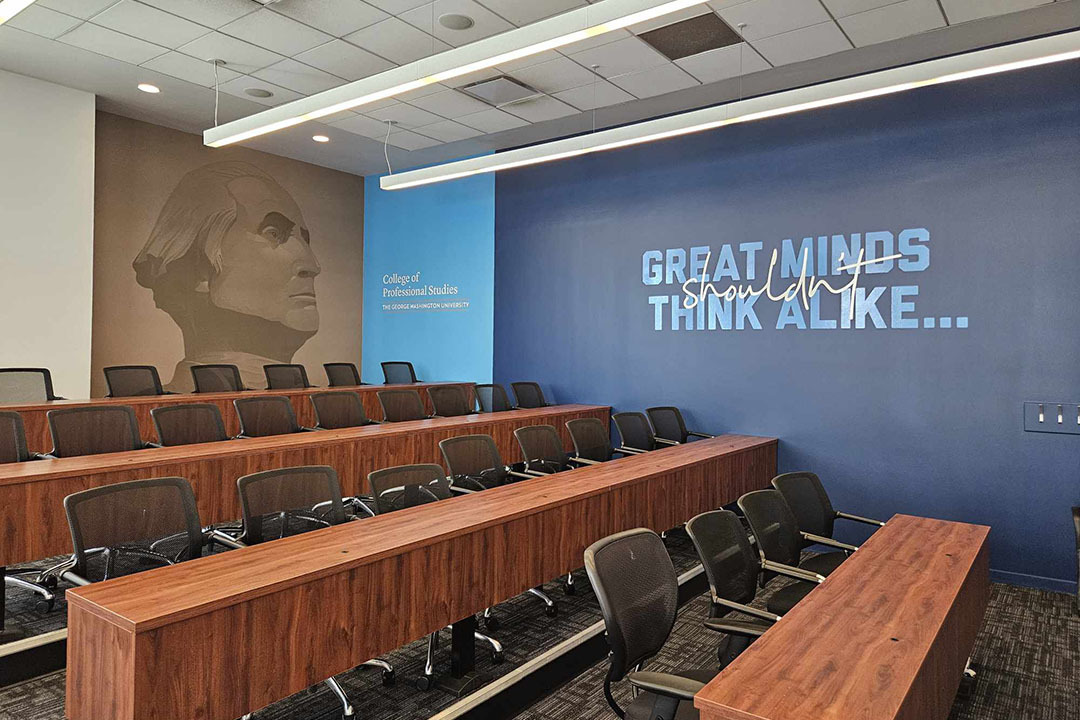 Lecture hall with a dark blue wall with Catalyst branded text on it that reads "Great minds shouldn't think alike."