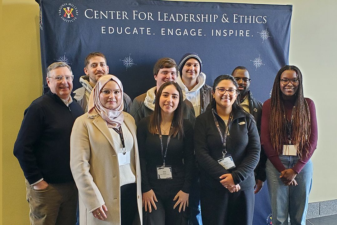 Group of cybersecurity students pose in front of a Center for Leadership and Ethics banner