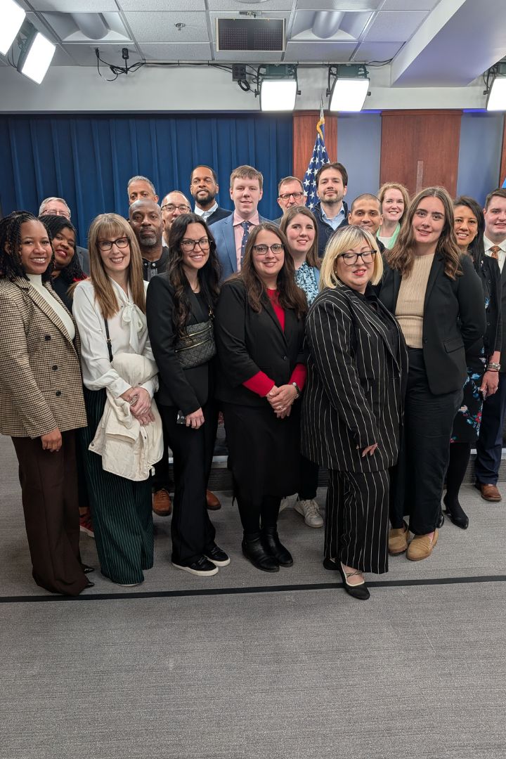 Group of students pose in Pentagon press room with Nancy Youssef, Pentagon Correspondent, Wall Street Journal