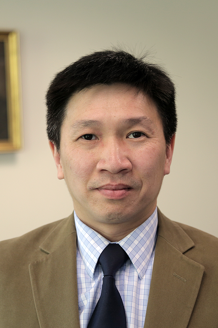 Man with short dark hair and eyes, beige blazer, dark tie, collared light shirt