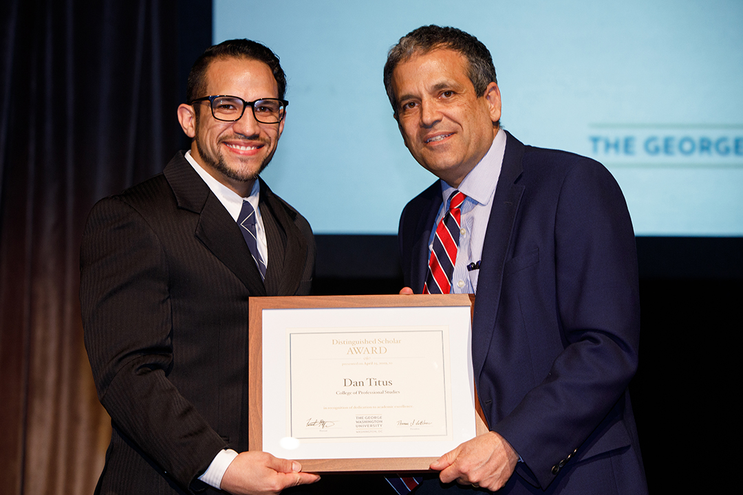 Dan Titus (left) accepting award he is holding from Provost Maltzman, both in suits.