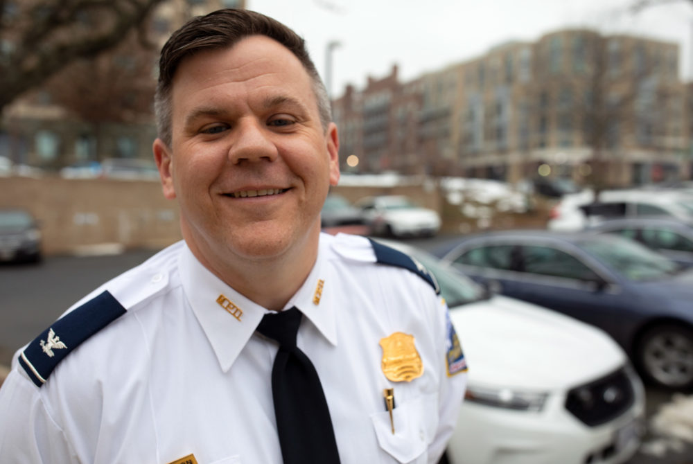 Duncan Bedlion smiling with cars behind him in his police uniform with badge