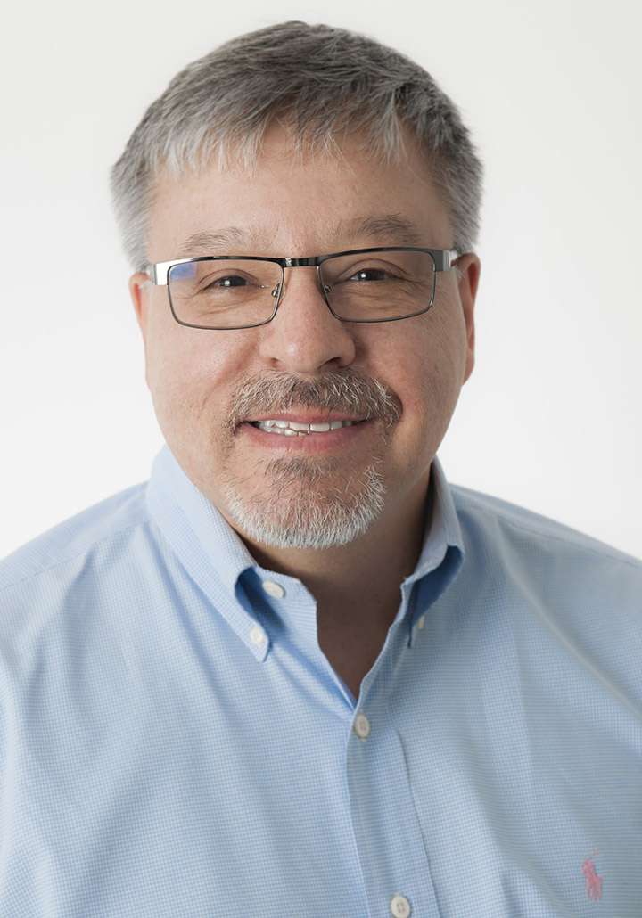 Headshot of man with salt and pepper hair and glasses in blue button down shirt