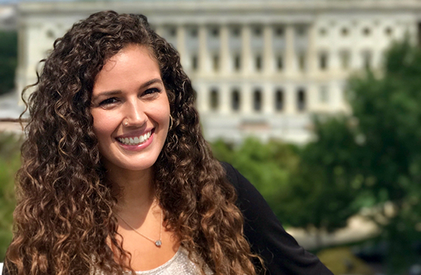 Elizabeth Rule with long brown curly hair in front of the U.S. Capitol