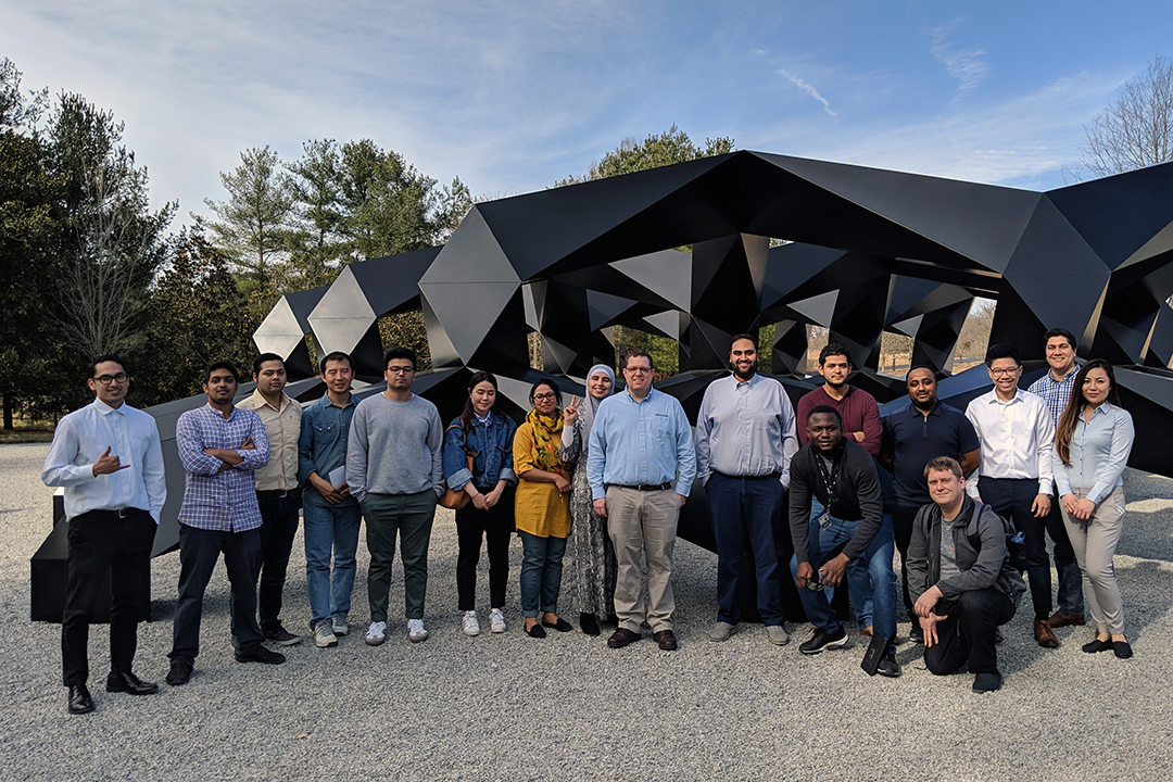 Large IIST student group of approximately 20 people in front of a black metal abstract sculpture