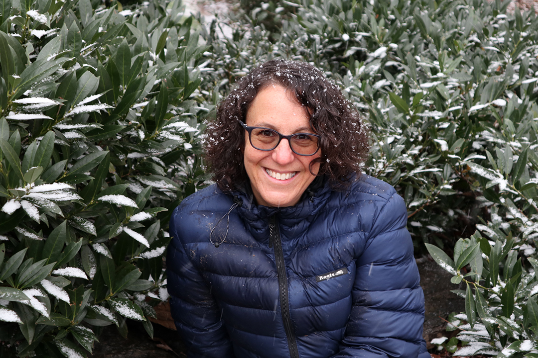 Melissa Feuer wearing a coat with green bushes and snow on them and her