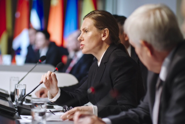 People at table with mics and inernational flags