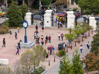 GW campus quad with bricks, tall clock, trees, students milling about