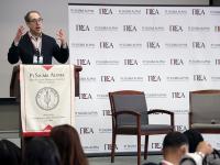 Matt Dallek speaking at a podium, next to a Pi Sigma Alpha Student Conference step-and-repeat