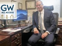 Todd Belt at his desk, GW all access logo to his left