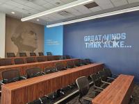 Lecture hall with a dark blue wall with Catalyst branded text on it that reads "Great minds shouldn't think alike."
