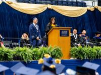 Christopher Linares with Tierney Pitzer at Commencement Celebration on the stage in regalia