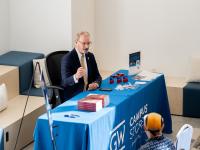 Todd Belt sitting at a GW campus store table, signing copies of his new book