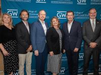 Lesley Lopez, Casey Burgat, Anthony Shop, Dean Riddle, Terry Szuplat, and Todd Belt smiling and posing in front of GW step-and-repeat