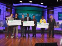 New Venture Competition winners standing onstage holding oversized checks
