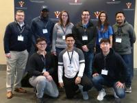 Group of 8 diverse students and 1 faculty member at the competition in a formal group photo.