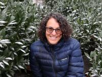 Melissa Feuer wearing a coat with green bushes and snow on them and her