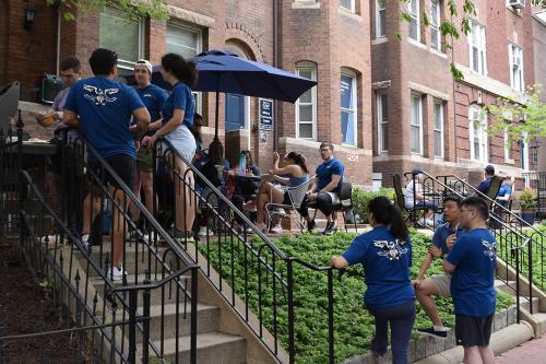 group of students outside a brick building with stairs and wearing matching blue tshirts