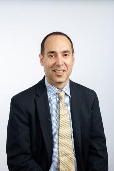 Dallek in dark suit, collared shirt, light tie with dark short hair