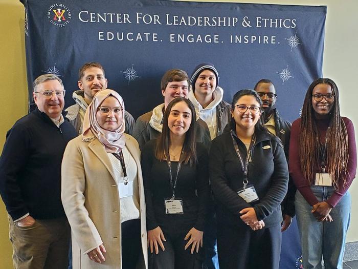 Group of cybersecurity students pose in front of a Center for Leadership and Ethics banner
