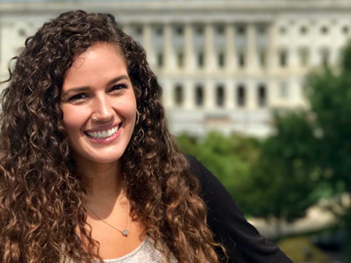 Elizabeth Rule with long brown curly hair in front of the U.S. Capitol