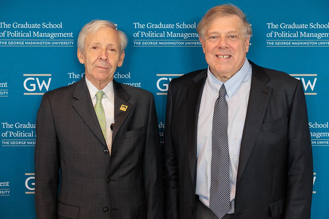 Dr. Christopher Arterton and Mark Penn standing in front of a GW step-and-repeat