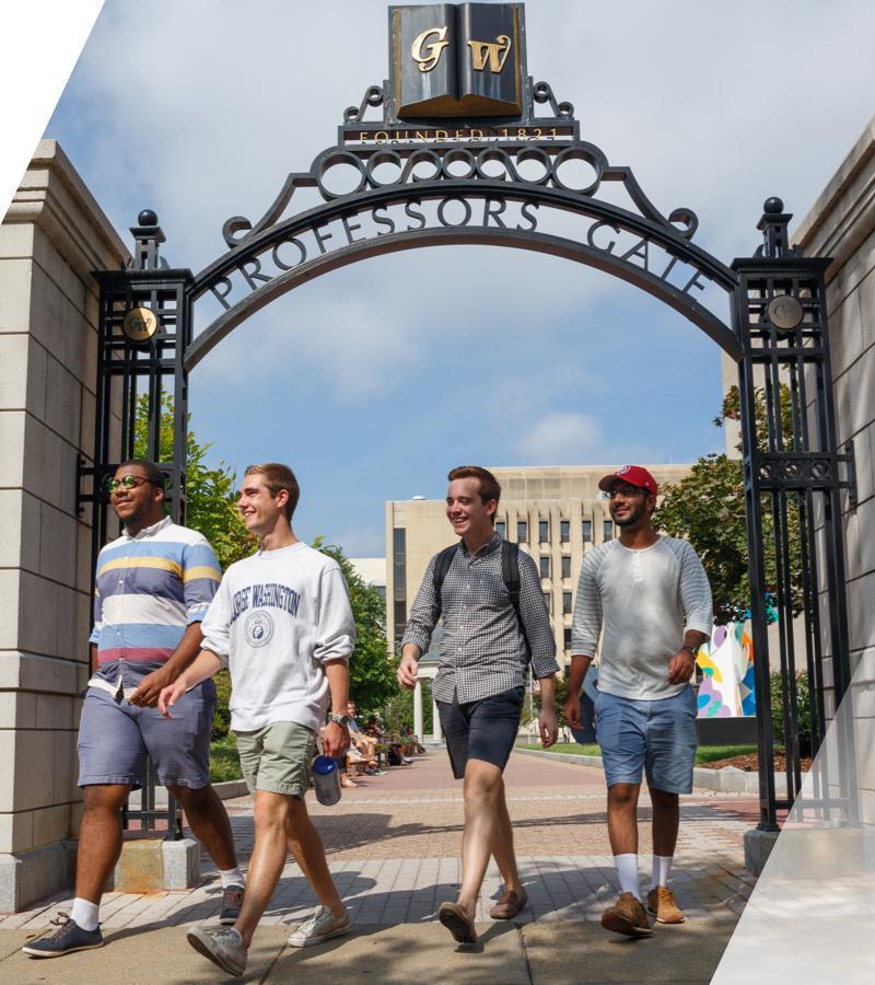 4 male college age students outside near the GW arch with letters GW above their heads