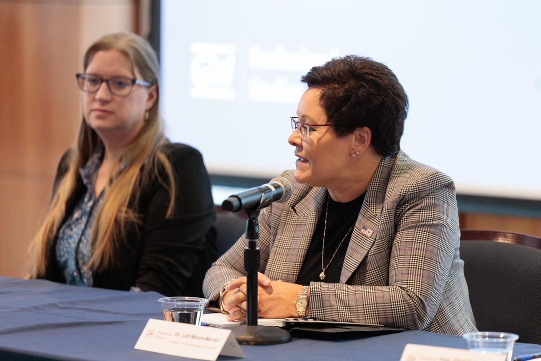 Dr. Christine de Souza and Dr. Lori Moore-Merrell sitting at podium