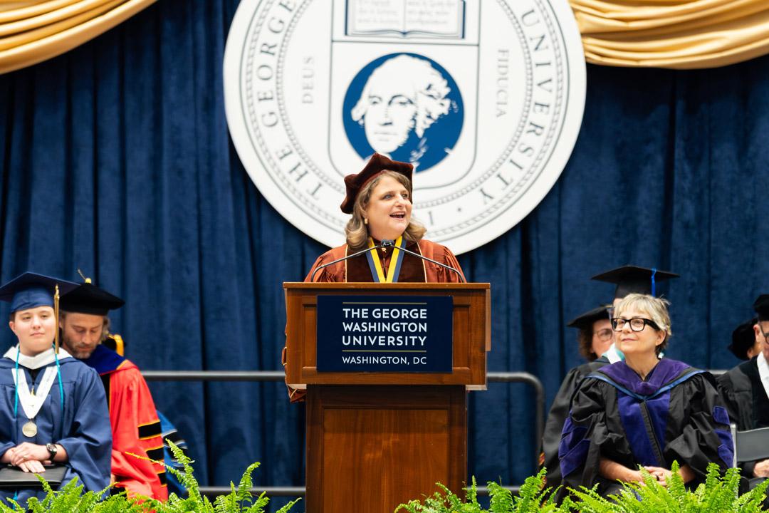 Dean Liesl Riddle stands at a podium onstage speaking