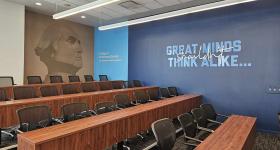 Lecture hall with a dark blue wall with Catalyst branded text on it that reads "Great minds shouldn't think alike."