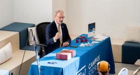 Todd Belt sitting at a GW campus store table, signing copies of his new book
